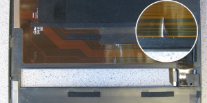 Das aufgefaltete Display-Folienkabel ist in der Mitte beschädigt (siehe vergrößerten Ausschnitt).