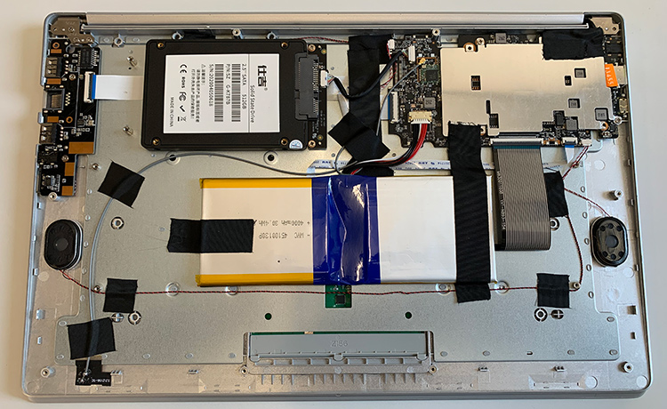 Das karge Innenleben des T-BAO: Links das I/O Board mit USB- und LAN-Anschluss, daneben die SSD-Festplatte, rechts oben das ziemlich kleine Mainboard. Die CPU wird lüfterlos über das Blech gekühlt. Unten mittig der eingeklebte Notebook-Akku.