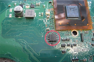 Mit rotem Kreis markiert: Der BIOS Chip. Oben rechts die CPU des ASUS. Beides befindet sich auf der Unterseite des Mainboards.